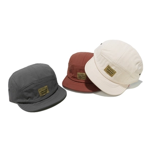 Three minimalist five-panel short brim baseball caps in grey, brick red, and off-white colors