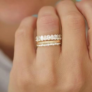Set di tre anelli dorati con zircone a goccia e pavé indossati sulle dita