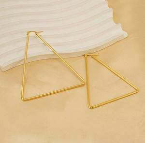 Macro shot of large golden triangle hoop earrings on gold silk with stone accent