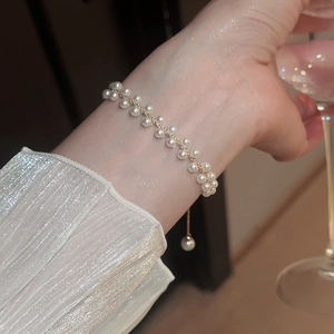 Gros plan d'un bracelet en perles à double rangée avec chaîne dorée au poignet féminin