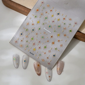 Close-up of gold starburst nail stickers with colorful gemstones and finished nail art