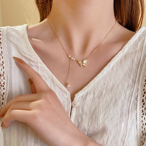 Collier papillon plaqué or avec nacre et perles porté par un mannequin élégant