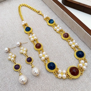 Macro detail of vintage gold necklace and earrings set with faux pearls and gems