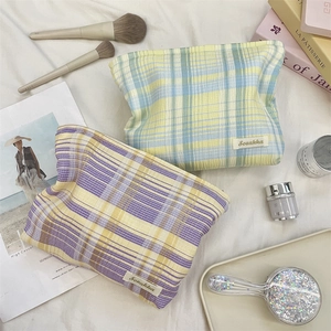 Close-up of colorful checkered fabric cosmetic bags with zipper and brand label details