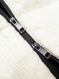 Detail of white knit ski jacket featuring a functional black double metal zipper closure