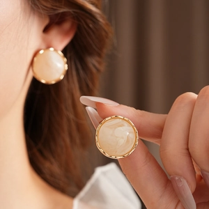 Close-up of French vintage beige round earrings with a detailed golden wavy border