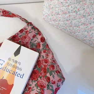 Détail du sac en toile jacquard à roses rouges et pochette matelassée à fleurs bleues
