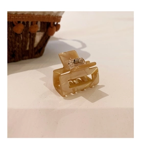 Detailed view of square acetate hair claw clip with cream marble texture and metal spring
