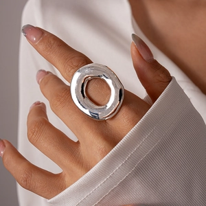 Macro shot of minimalist silver irregular hollow ring showing polished metal texture