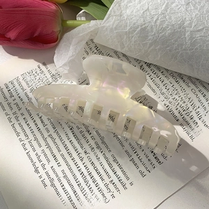 Detail of translucent mermaid finish acetate hair claw clip on a vintage book background