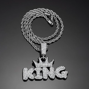 Close-up of iced out KING pendant with crown detail and sparkling crystal rhinestones