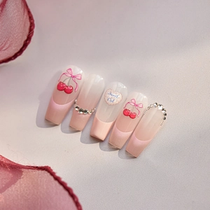 Detail of pink gradient press-on nails with cherry motifs and bow decorations