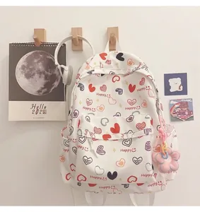 Close-up of white canvas backpack with colorful heart prints and flower plush keychain