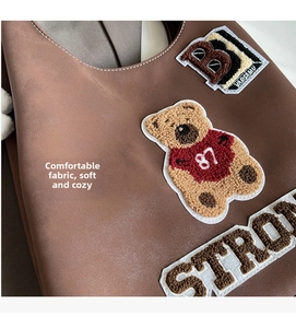 Dettaglio della borsa tote marrone vintage con ricami di orsetto e lettere patch