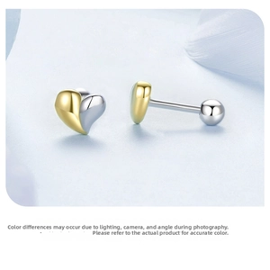 Macro detail of two-tone gold and silver heart stud earrings with secure screw backs