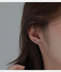 Détail de trois petites boucles d'oreilles à vis en formes d'étoile et de cœur