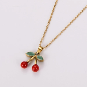 Close-up of gold chain necklace with red cherry pendant and green leaf detail