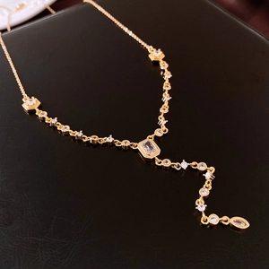 Detail of gold-plated Y-shaped tassel necklace with sparkling cubic zirconia on black leather