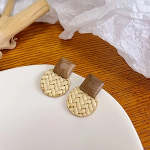 Close-up of handmade geometric woven earrings with square wood and round straw design