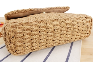 Close-up of hand-woven straw crossbody bag showing cross-stitch texture and metal clasp