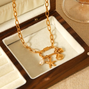 Detalle de colgantes de estrella de mar, concha y perla en collar de acero de oro de 18K