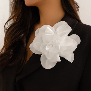 Detail of a large white layered organza flower brooch on a black suit lapel