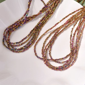 Macro shot of 2mm iridescent hematite square beads strand on a white shell tray