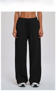 Detail of loose black wide-leg sports trousers with drawstring waist and knit fabric