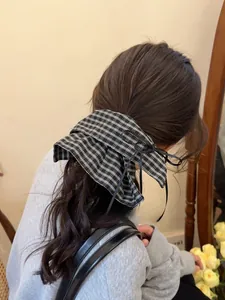 Detail of black and white plaid bow hair tie with ribbons on long wavy hair
