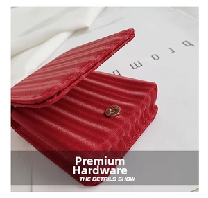 Detail of red textured leather mini makeup bag with golden metal magnetic clasp