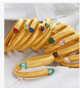 Detailed macro view of gold-plated spiral snake bracelets with heart-shaped colorful zircons