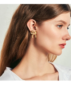 Close-up of elegant gold bow earrings worn by a model showcasing a polished finish
