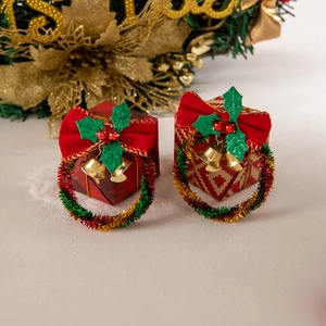 Close-up of festive red gift box earrings with green wreaths and tiny gold bells
