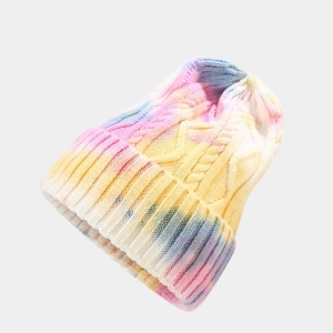 Detailed close-up of rainbow tie-dye cable knit texture on a warm winter beanie hat
