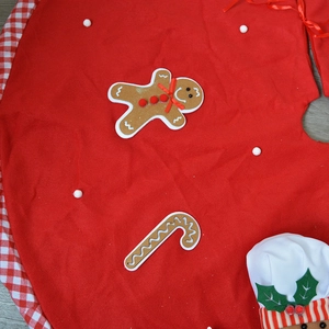 Red Christmas tree skirt with gingerbread man applique and white pom-pom trim details