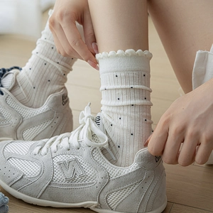 Chaussettes en tricot beige à pois portées avec des baskets rétro sur un sol en bois