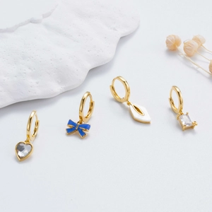 Goldene Creolen-Sets mit Herz-Kristall, blauem Bogen und geometrischen Anhängern auf Weiß