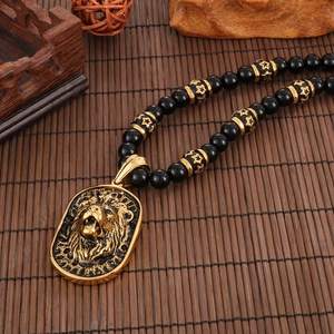 Detail of golden lion head pendant on black beaded necklace with star pattern spacer beads