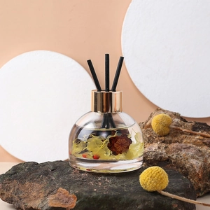 Car aromatherapy glass bottle with yellow dried flowers and black reeds on rock