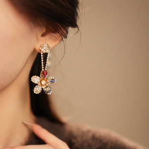 Macro shot of silver needle flower earrings with colorful crystals and pearl tassels