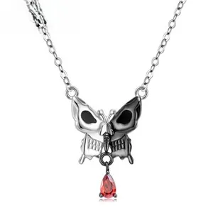 Macro shot of silver butterfly skull pendant with a vibrant red pear-cut zircon drop