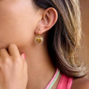 Close-up of heart-shaped gold stud earring with LOVE engraving and pave crystal border