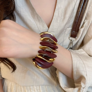 Detail shot of wide stretch bracelet with alternating burgundy matte and gold metal blocks