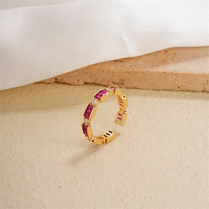 Detail of gold-plated open ring with pink baguette stones and white round zircon stones
