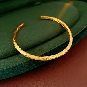 Detail of vintage gold brushed cuff bracelet with small gems in a green velvet box