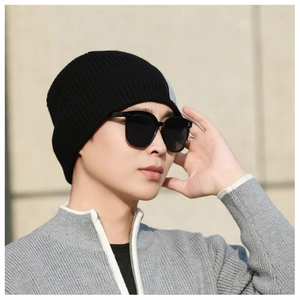 Nahaufnahme einer hochelastischen Rippstrick-Mütze an einem Model mit Sonnenbrille