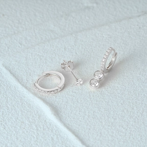 Detail of three-piece silver earring set featuring rhinestone hoops and a sparkling stud