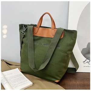 Close-up of green canvas tote bag with brown leather handles and Light Fashion print