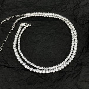 Detail of silver tennis chains with sparkling zircons and lobster clasp on black background