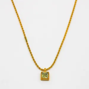 Détail d'un collier chaîne torsadée dorée avec pendentif zircon carré vert au style vintage
